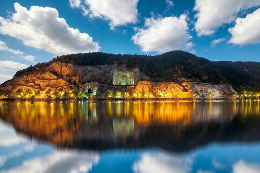 Ein See mit einem Berg im Hintergrund und einem Gebäude, das von Lichtern beleuchtet wird. 5