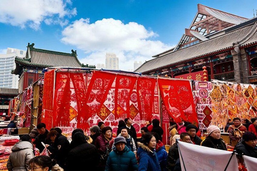 Ein traditionelles chinesisches Gebäude mit roten Verzierungen und einer Menschenmenge davor. 4