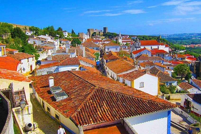 Un pueblo con edificios de tejados de teja, una iglesia destacada y una colina al fondo. 3