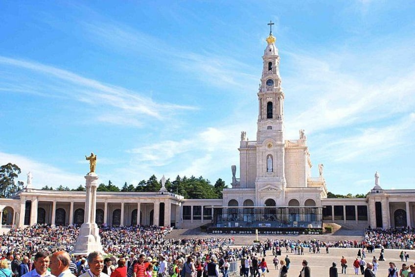 Una iglesia blanca grande con un campanario alto, rodeada de gente. 4