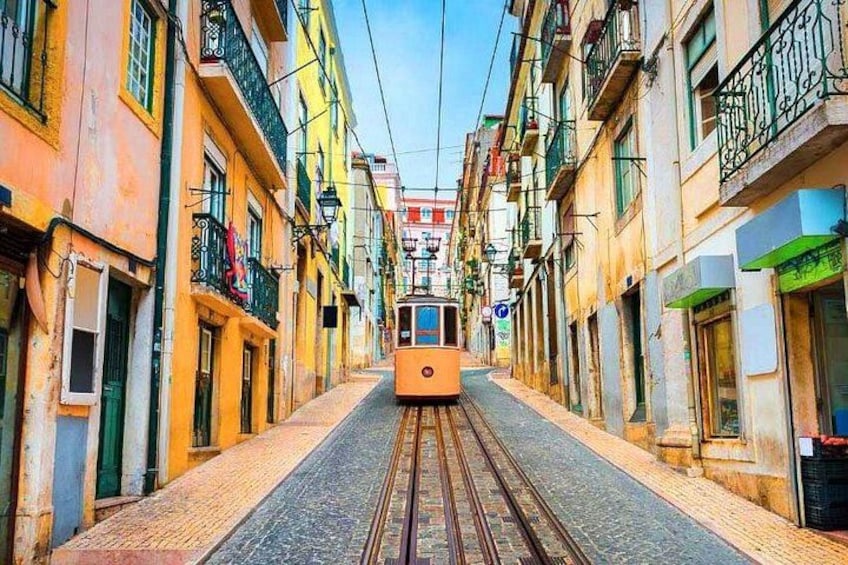 A tram on a narrow street flanked by colorful buildings. 1
