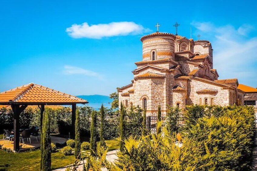 A church with a dome and crosses, surrounded by greenery and a clear sky. 2