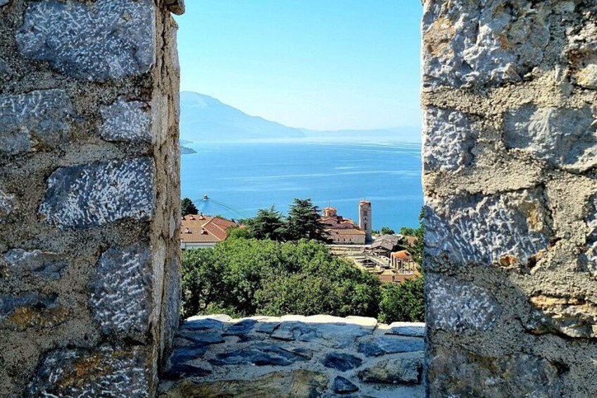A stone wall with a view of a coastal town and a mountain in the distance. 2