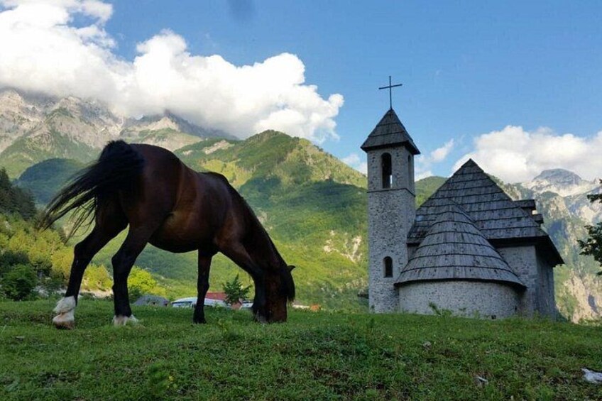 Un cavallo pascola vicino a una chiesa con montagne sullo sfondo. 2