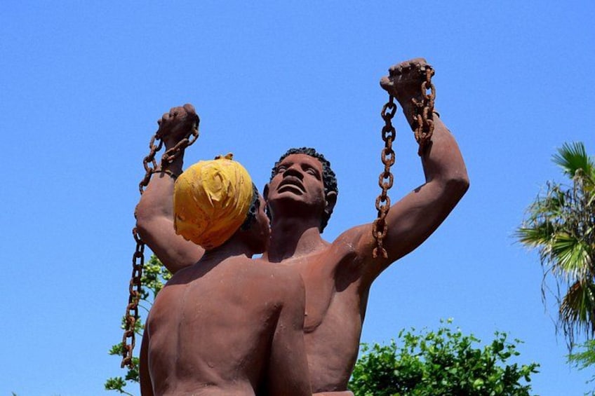 Una statua raffigura una figura muscolosa che tiene una catena e un oggetto giallo. 2