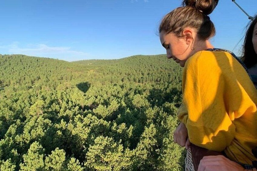 Una persona con suéter amarillo contemplando un denso paisaje boscoso bajo un cielo despejado. 5