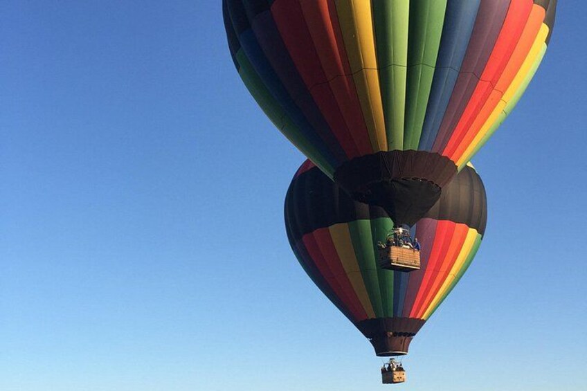 Un globo aerostático con múltiples franjas de colores sobre un cielo despejado. 3