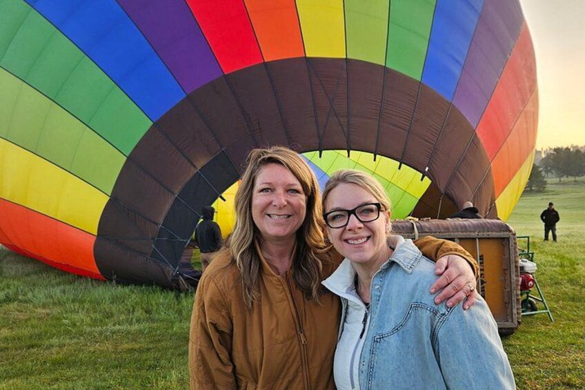 Dos personas de pie frente a un gran globo aerostático colorido. 2