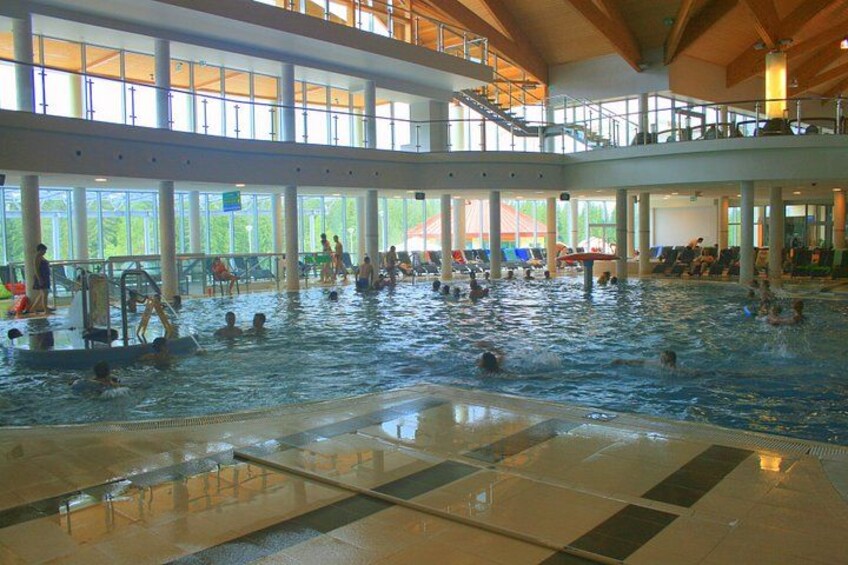 Una piscina interior con varias pistas de natación, gente nadando y un puesto de socorrista. 1