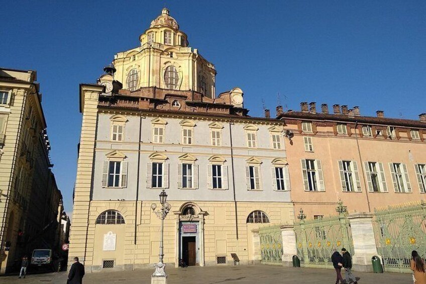 A historic building with a clock tower, a large arched entrance, and a decorative gate. 2
