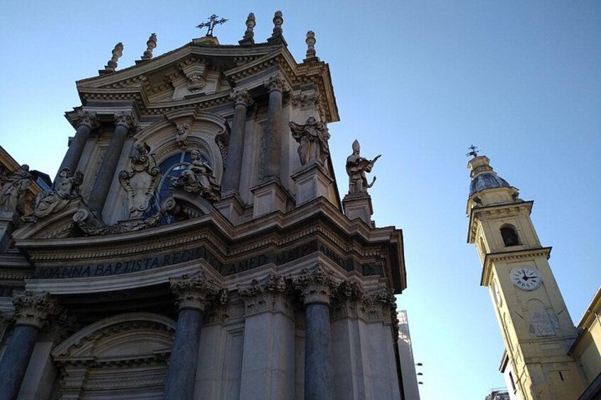 A historic building with ornate architecture, including columns and statues, and a clock tower in the background. 2