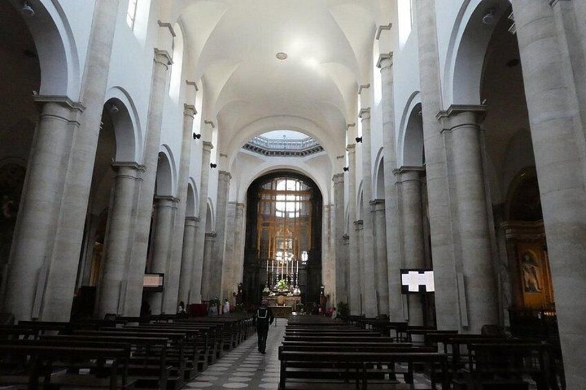 A church interior with rows of pews, a central altar, and arched ceilings. 4