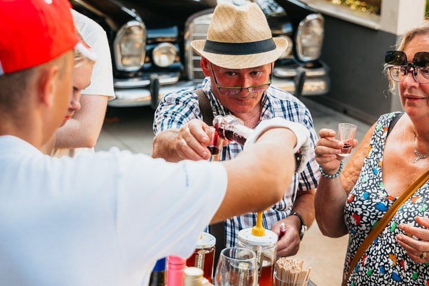 A group of people toasting with drinks at a car show. 3