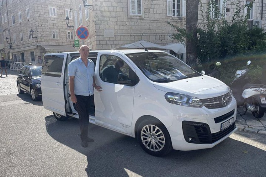 A white van parked on a street with a man standing beside it. 2
