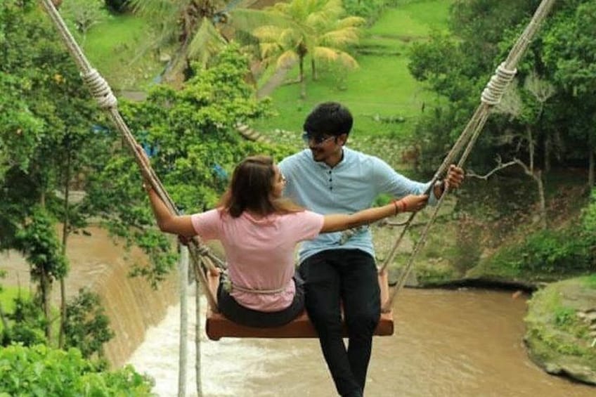 Two people on a rope swing over a river. 2