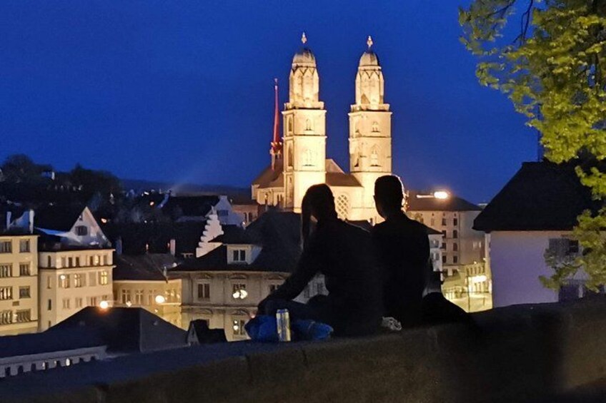 A couple sitting on a ledge overlooking a historic building with two towers. 2