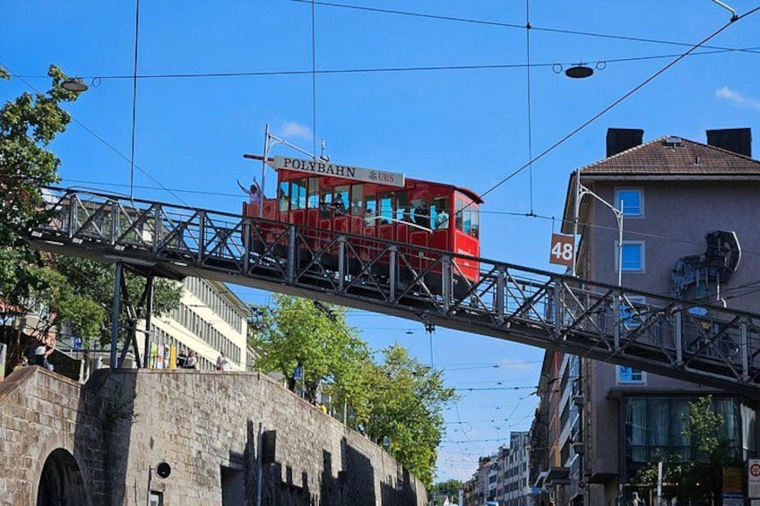 A red tram on an elevated track, a stone bridge, and a building with the number 48. 5