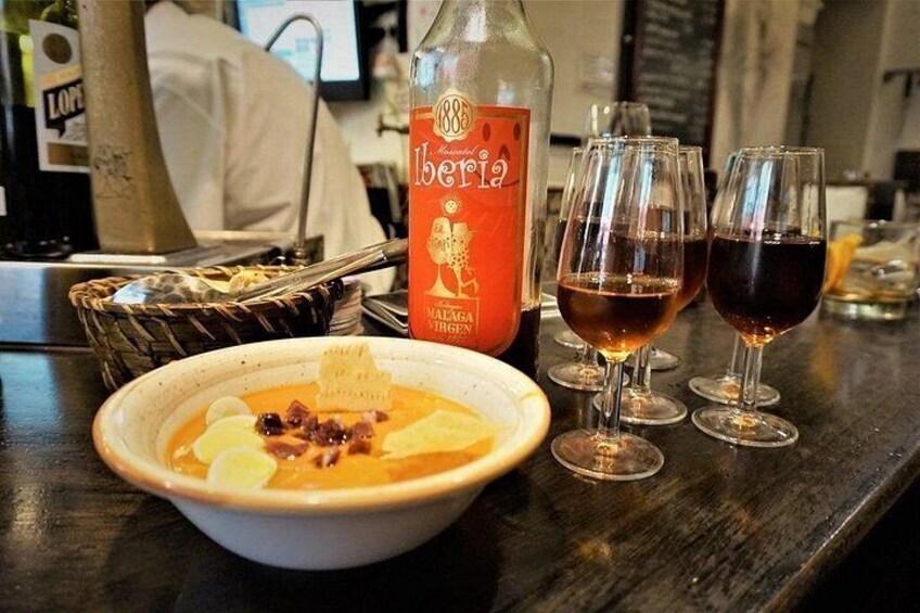 Eine Schüssel Suppe, eine Flasche Iberia-Wein und drei Weingläser auf einem Tisch. 2