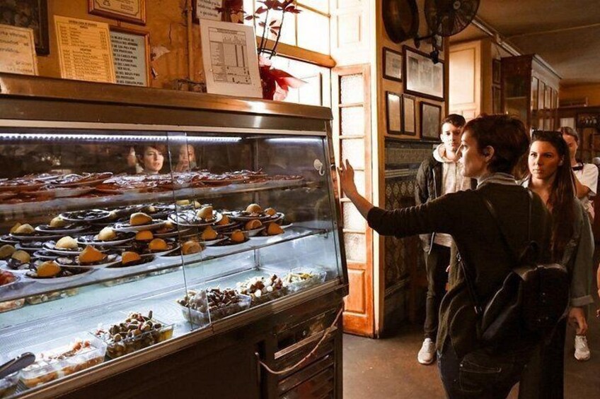 A bakery display case with pastries and a person pointing at it. 4