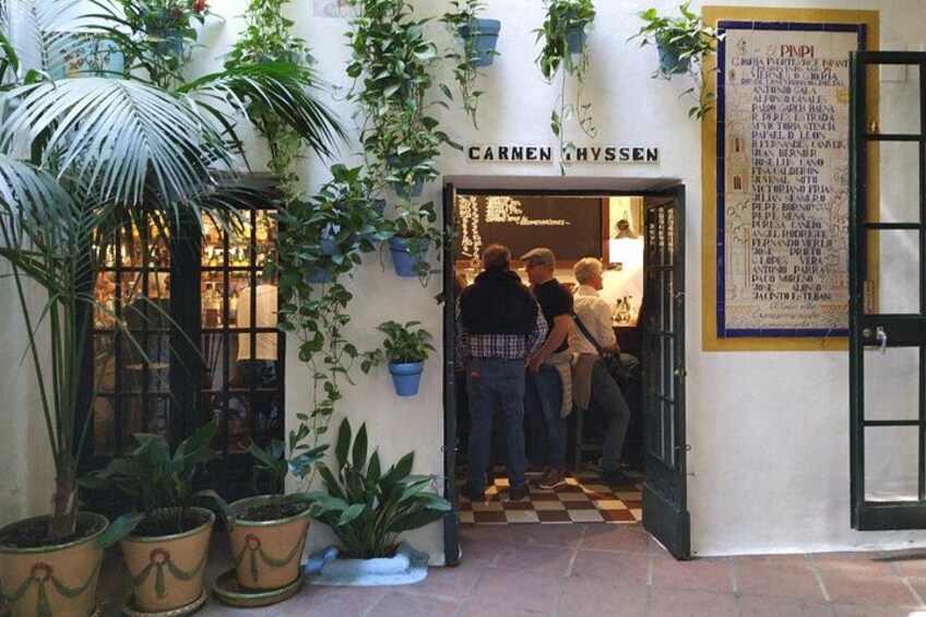 Fachada de un local llamado 'Carmen Hyvssen', con plantas en macetas y un suelo a cuadros. 2