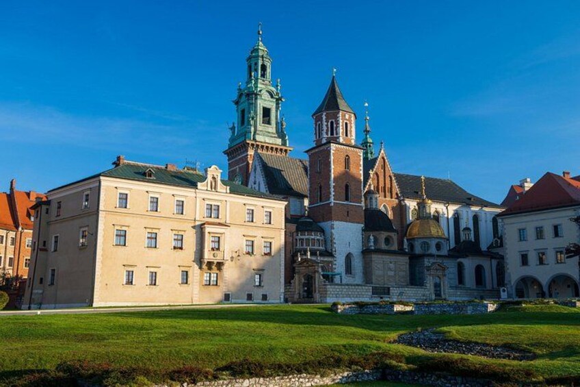A historic building with a clock tower, a church with a dome, and a well-maintained lawn. 2