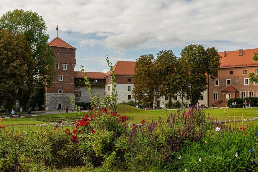 A historic building with a tower, surrounded by a well-maintained garden with various plants and flowers. 3