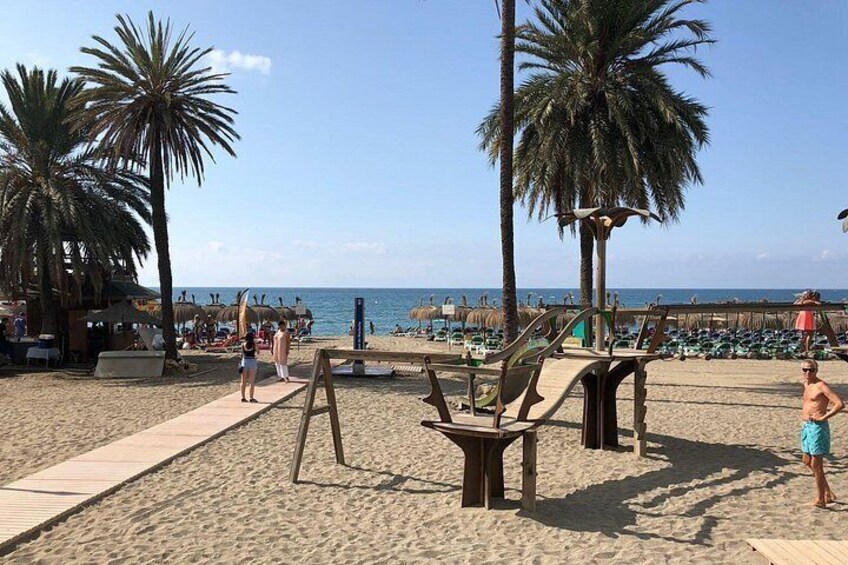 Una playa con palmeras, una terraza de madera y sillas de playa. 2