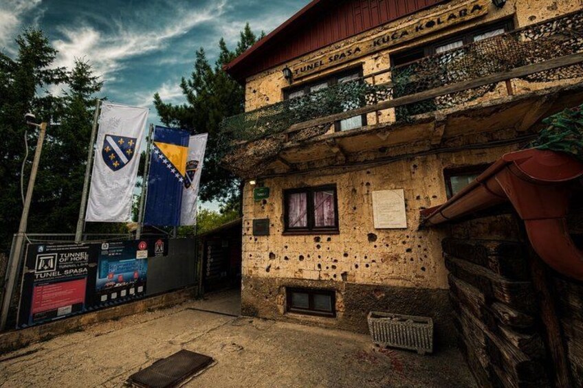 A building with a stone facade, a balcony, and flags. 3