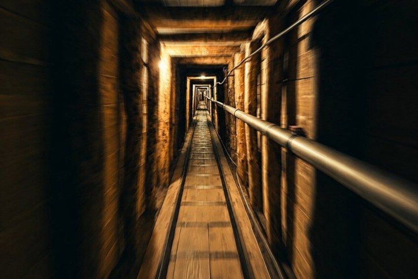A long, narrow corridor with wooden walls and a central walkway. 5