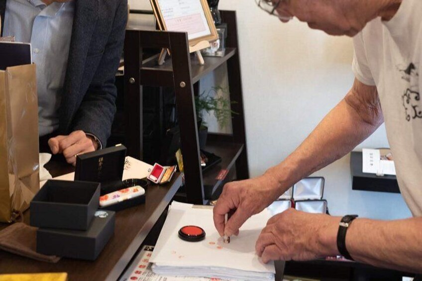 Una persona manipulando documentos en un escritorio con una computadora y diversos objetos. 1