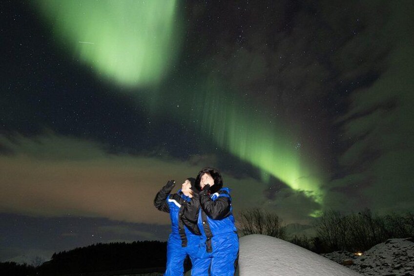 Two people observing the Northern Lights in a snowy landscape. 5