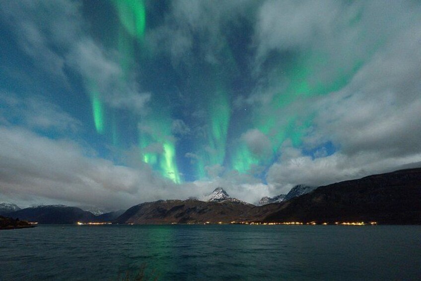 The Northern Lights over a mountainous landscape with a body of water in the foreground. 3
