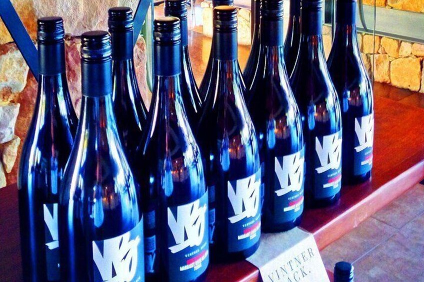 Varias botellas de vino con etiquetas, dispuestas en una estantería. 4