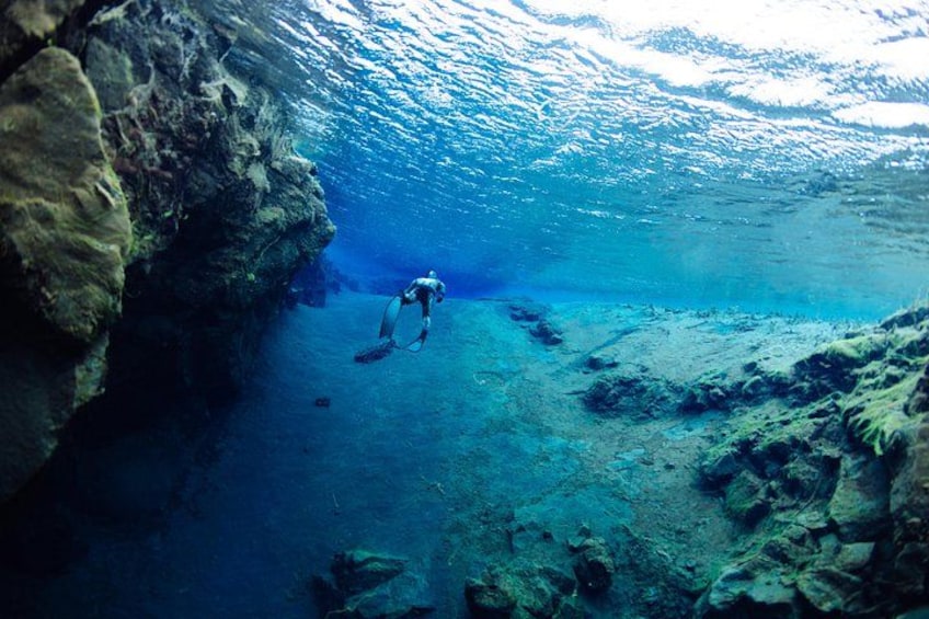 A diver underwater near a rocky cliff. 3