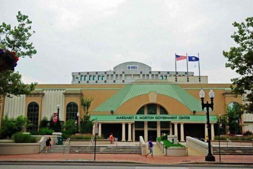 A government building with a green roof, a flagpole with the American flag, and a sign reading 'Margaret E. Morton Government Center.' 5