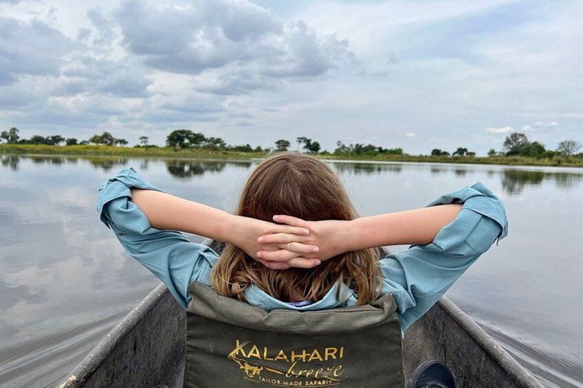 A person in a boat with a water body and trees in the background. 1