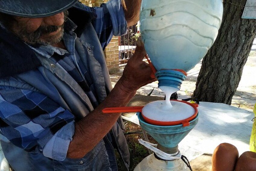 A person pouring a white liquid from a container into a blue funnel. 4