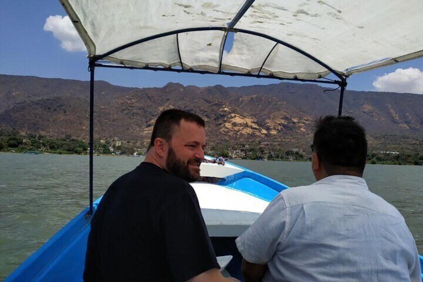 Two people on a boat with a mountainous landscape in the background. 2