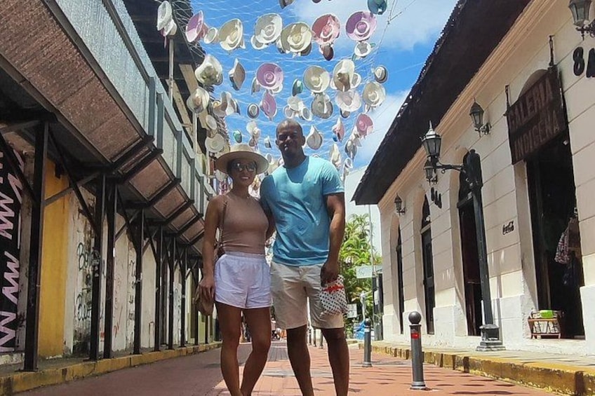 A street with buildings, a man and a woman walking, and a decorative ceiling with hanging objects. 5