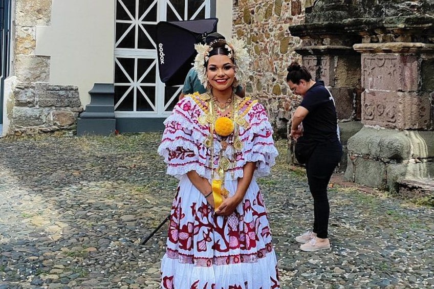 A person in traditional attire standing in front of a stone building with a window and a door. 2