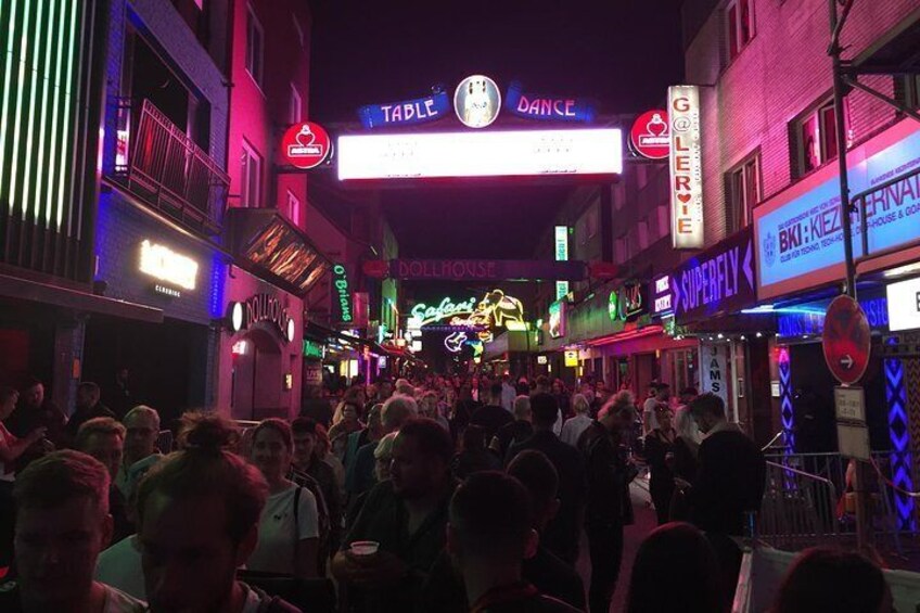 Calle concurrida por la noche, con letreros de neón y un letrero que dice 'Table Dance'. 4