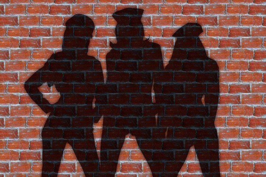 Un muro de ladrillo con tres siluetas de personas. 3