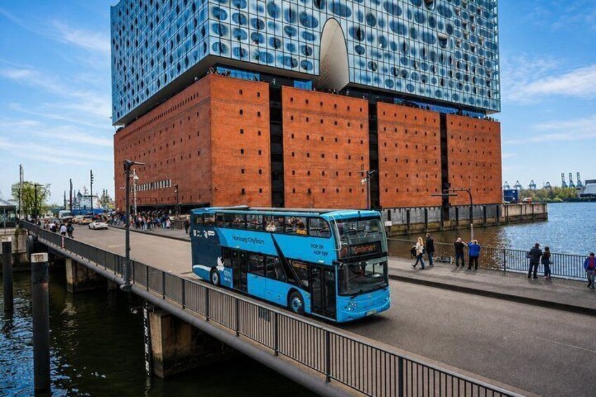 A blue double-decker bus on a bridge, a modern building with a reflective facade, and a river. 4