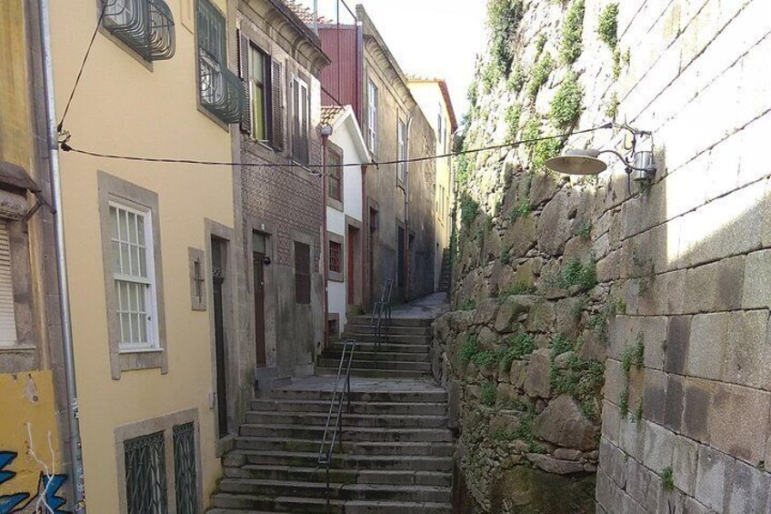Un callejón estrecho con una pared de piedra a un lado y un edificio amarillo al otro. 2
