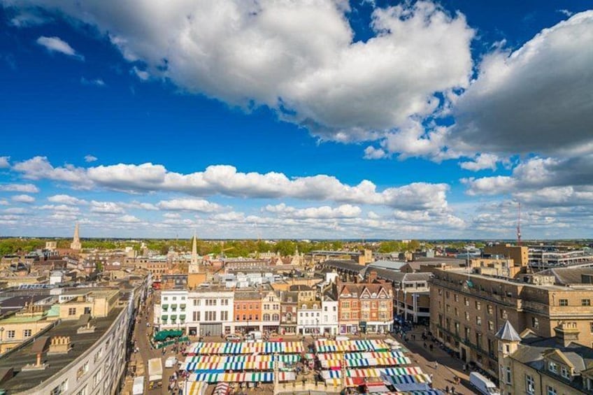 Une vue urbaine comprenant une vaste zone de marché en plein air, des bâtiments historiques et un ciel bleu dégagé. 4