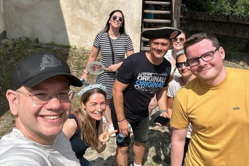 A group of people outdoors, some wearing casual clothing and hats, standing near a concrete structure with a metal staircase. 4