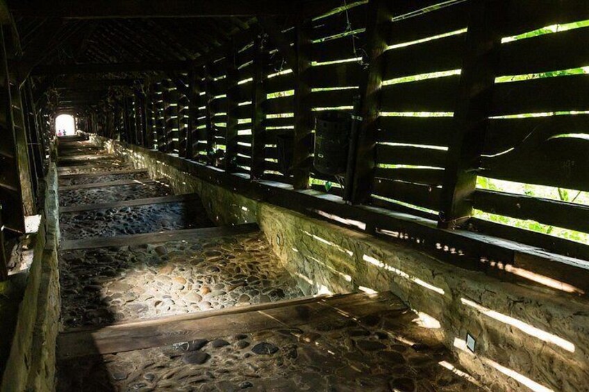 A stone-paved corridor with wooden slats and a stone wall. 3