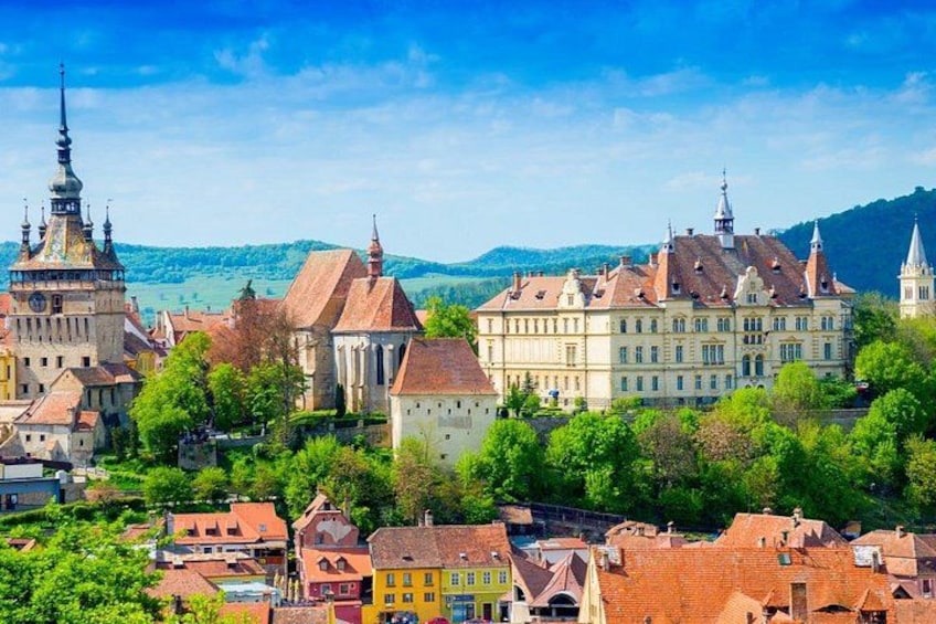 A historic town with a prominent church, a large castle, and surrounding greenery. 3