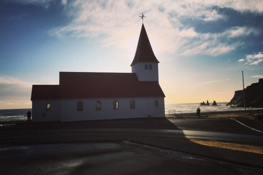 Una iglesia costera con techo rojo y campanario, con vista al mar. 5