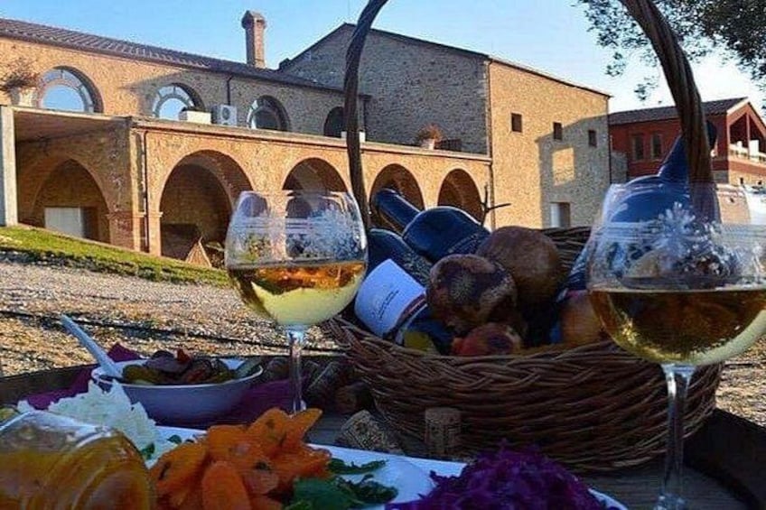 Una mesa con copas de vino, una cesta de pan y un edificio con arcos al fondo. 1